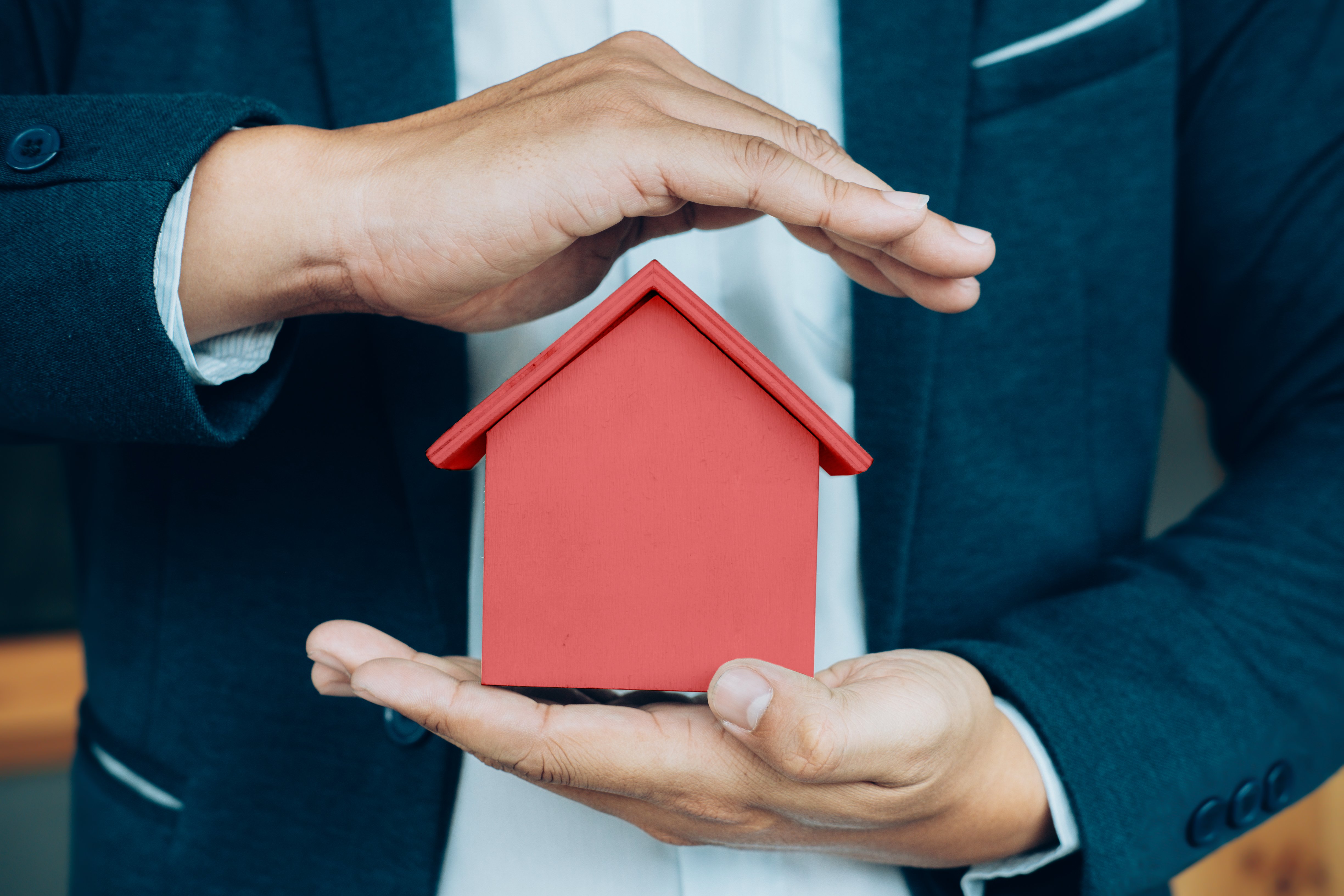 business-man-hand-hold-house-model-saving-small-house